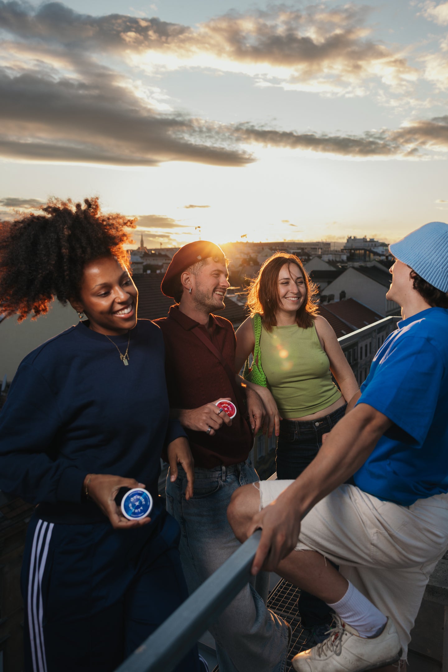 Freunde die gemeinsam im Sonnenuntergang auf der Rooftop Terrasse stehen.