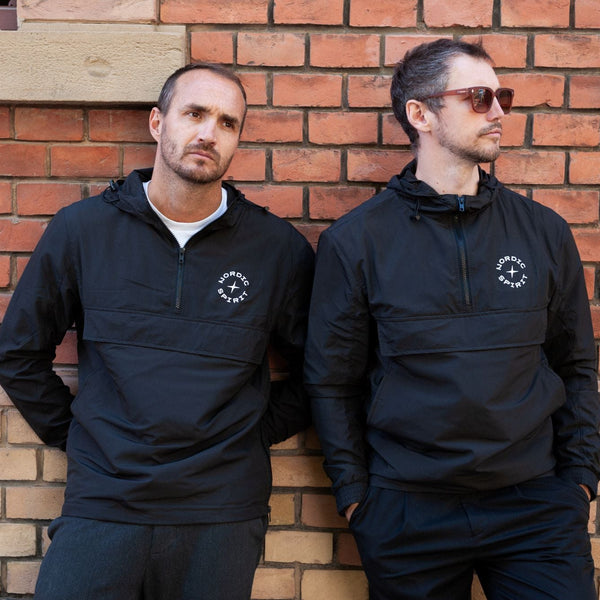 Zwei Personen mit Nordic Spirit Windbreakern vor Ziegelwand